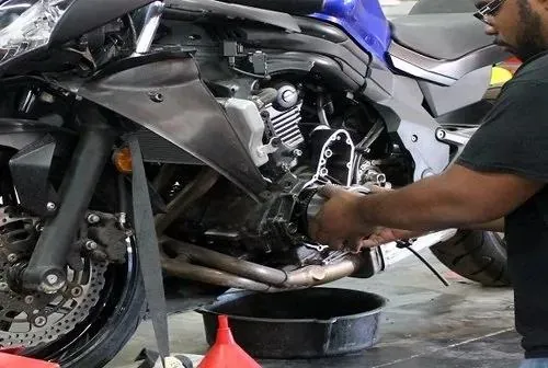 Technician draining engine oil from a motorcycle