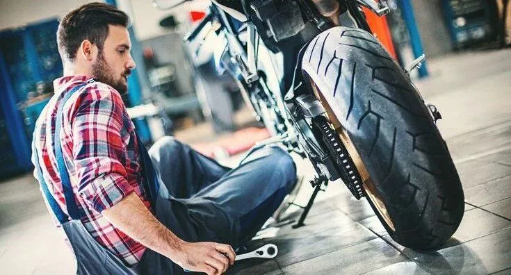 Mechanic inspecting a motorcycle rear tyre
